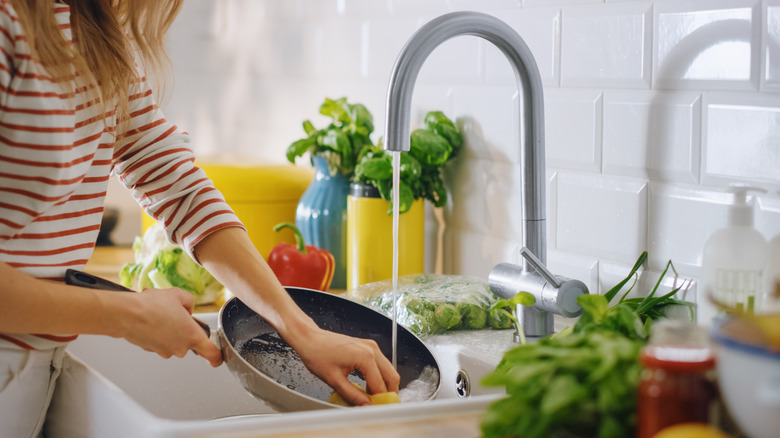 Person washing pan in sink