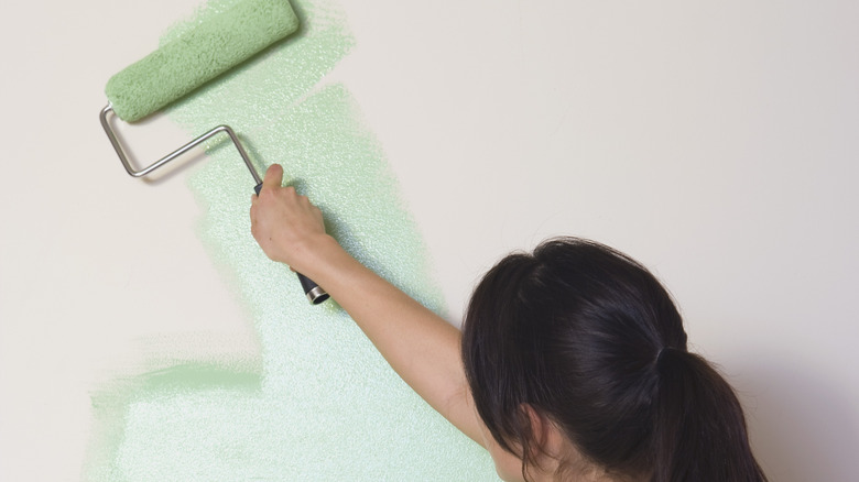 Woman painting a wall green