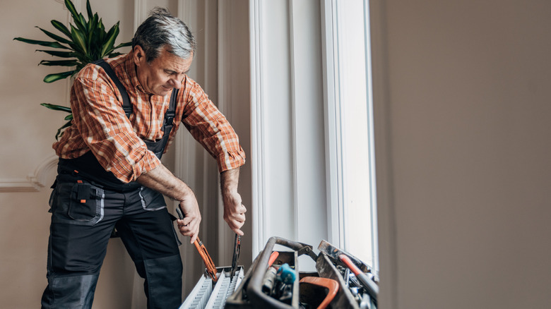 Older man fixes heating unit