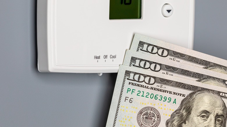 Hundred-dollar bills lying against a thermostat