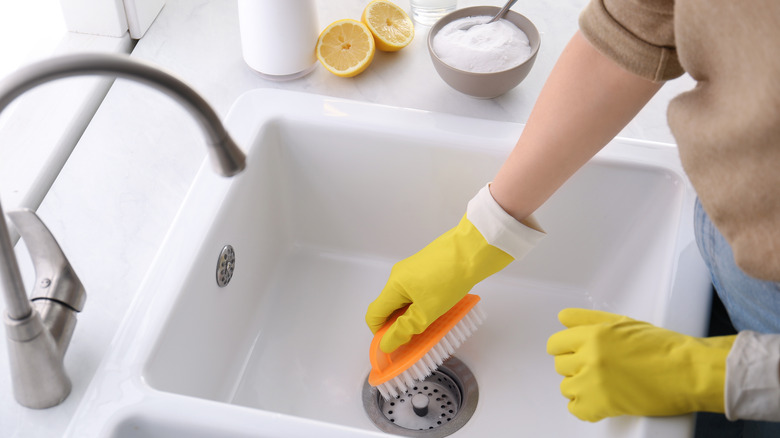 hands in gloves cleaning sink