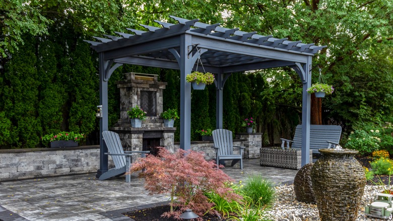 A patio area featuring pavers and a dark gray pergola