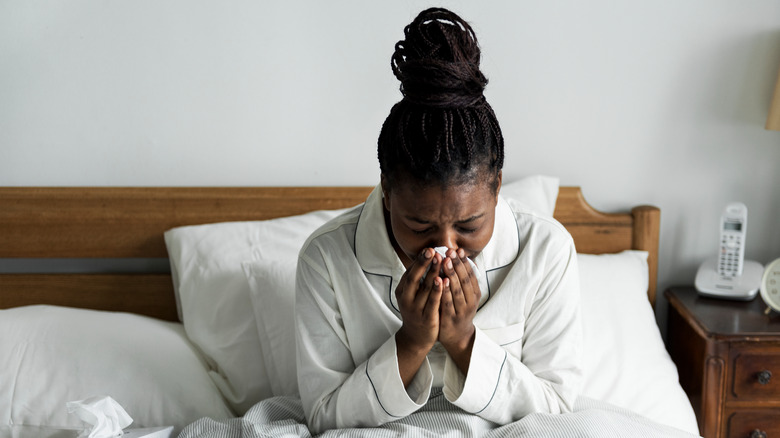 Woman blowing her nose in bed