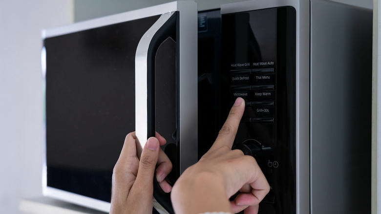 Hands using microwave keypad