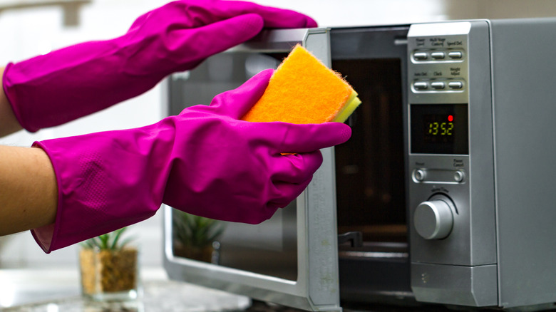 hands cleaning microwave