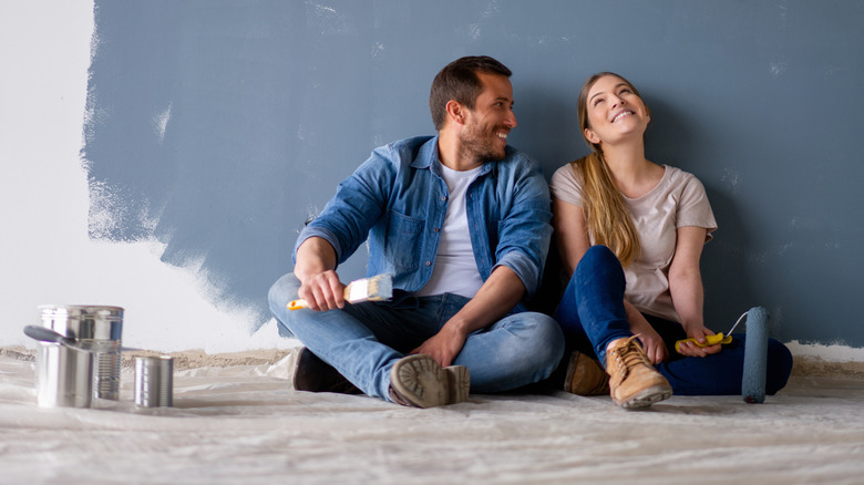 Two people sitting by painted wall