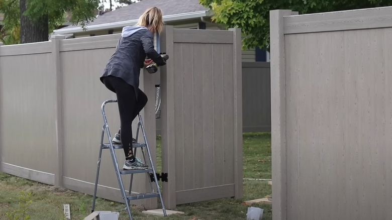 woman installing vinyl gate