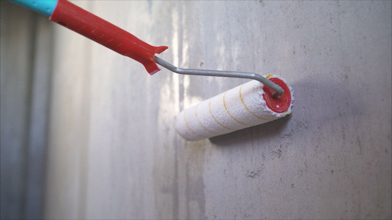 Roller applying primer to wall