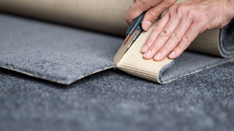 Person cutting carpet using knife