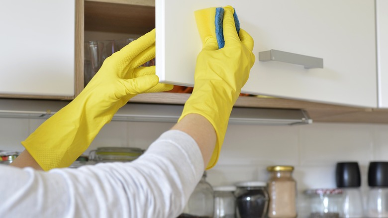 person cleaning kitchen cabinet