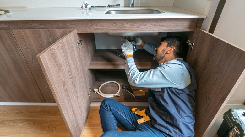 Plumber repairing leak to maintain a property