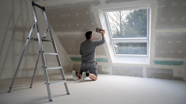 man working on attic wall