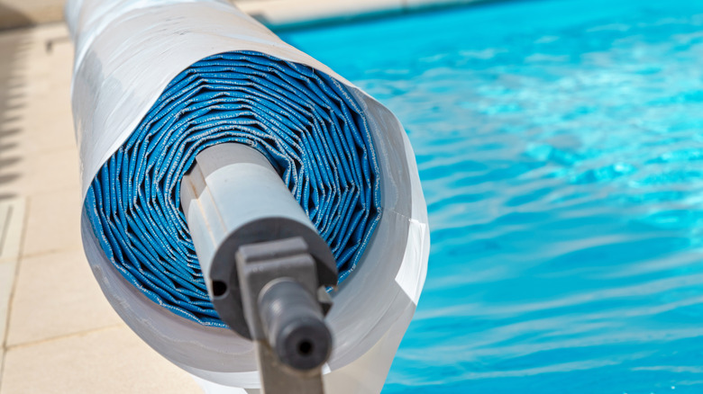 Pool cover rolled up next to pool