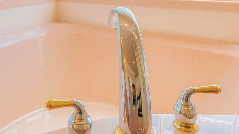 Bath faucet with silver spout and silver and gold knobs