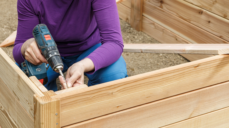 Woman constructs bed with electric drill