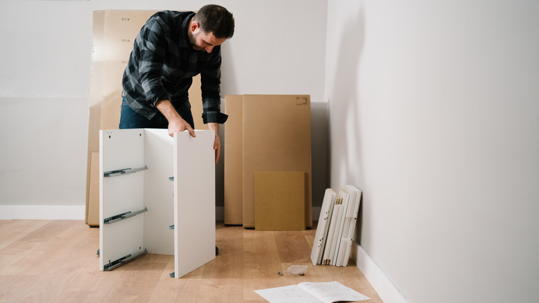 Man assembling white furniture