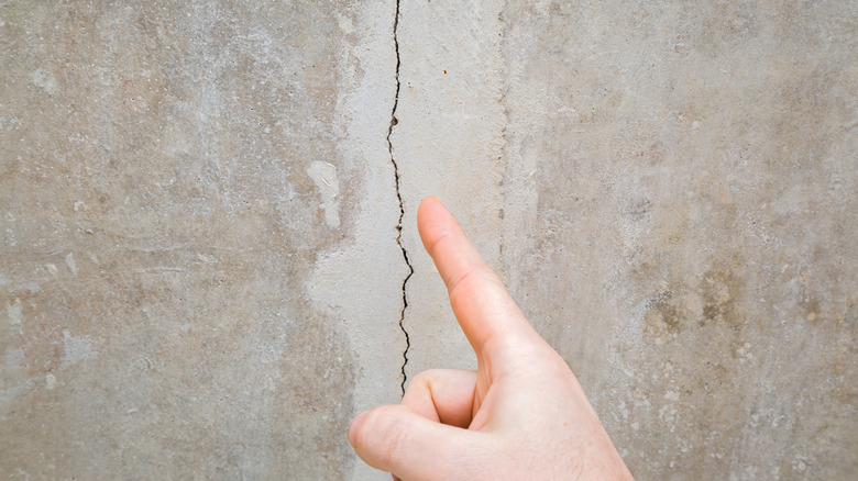 person pointing at foundation crack