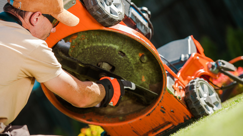 Man reassembles lawn mower blades