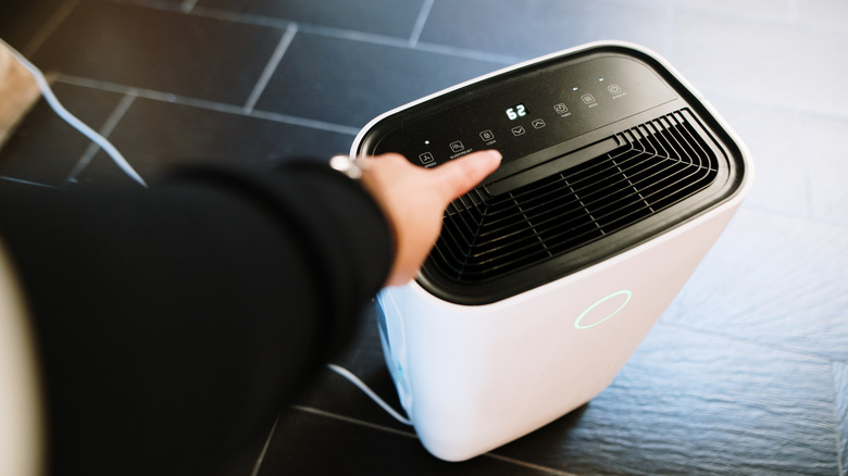 Person adjusting a dehumidifier to control humidity levels