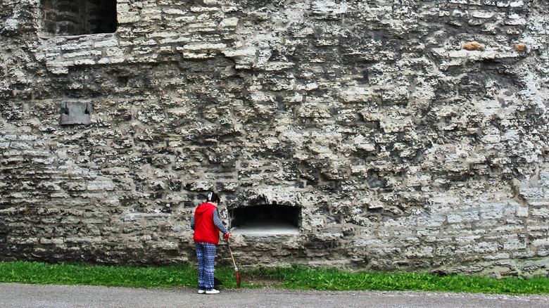 woman sweeping outside castle