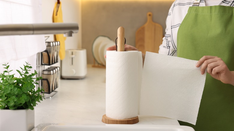 Woman tearing paper towel off roll