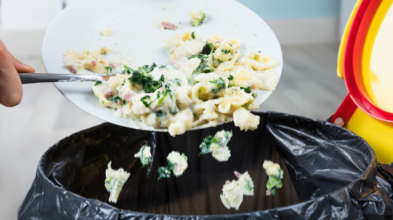 Person scraping pasta into trash