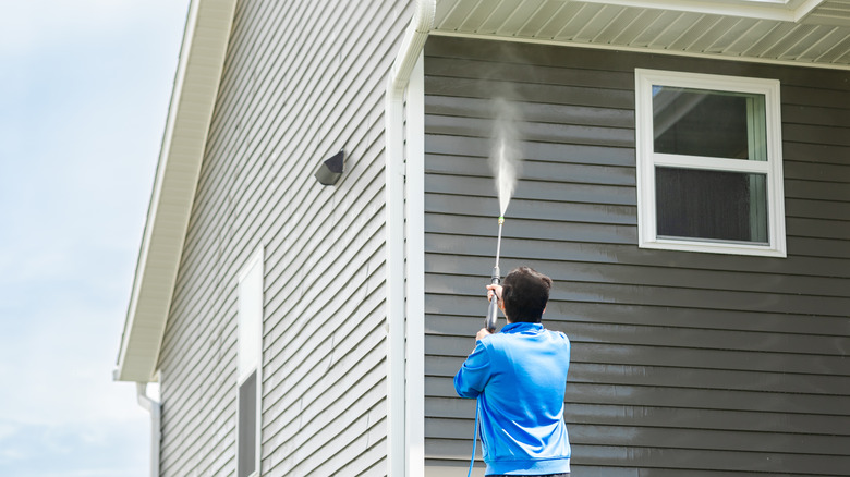 Person pressure washing house