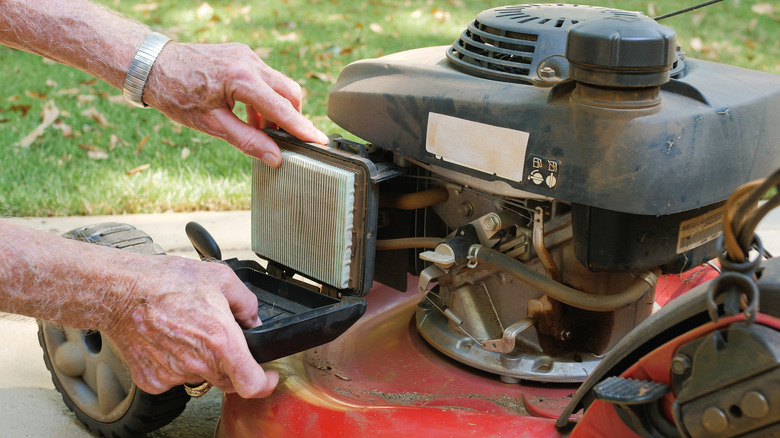 hands touching lawn mower air filter