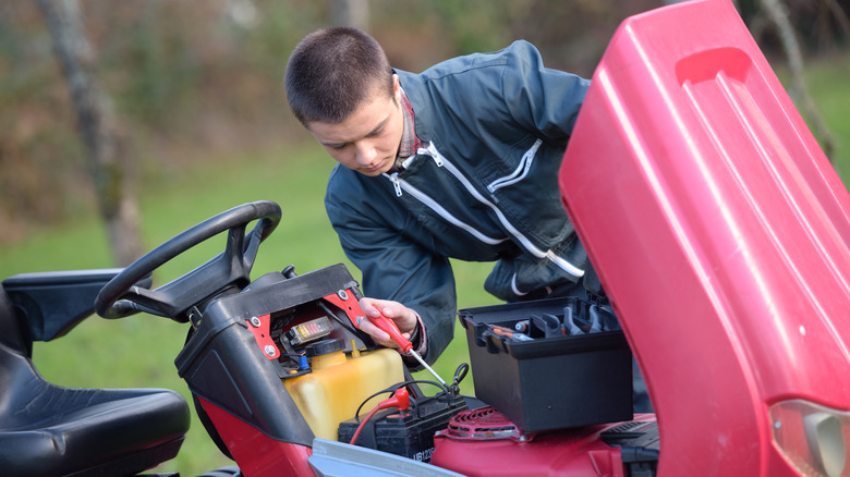 person connecting mower battery