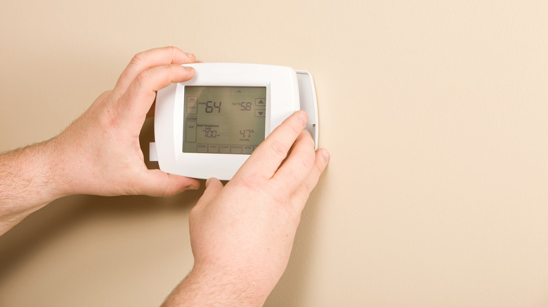 Hands on white thermostat