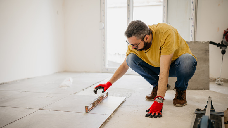 A person leveling flooring in a demolished bathroom