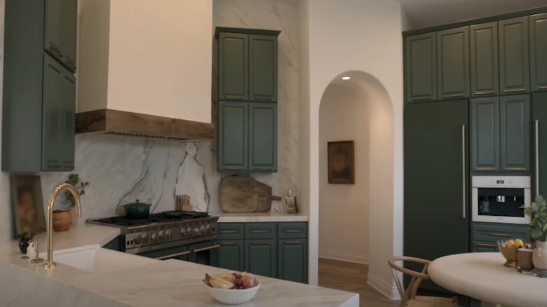 White veined marble countertops against green cabinets