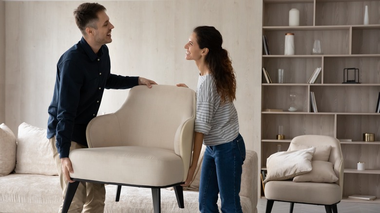 couple carrying beige chair