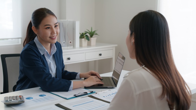 Two women speaking at desk