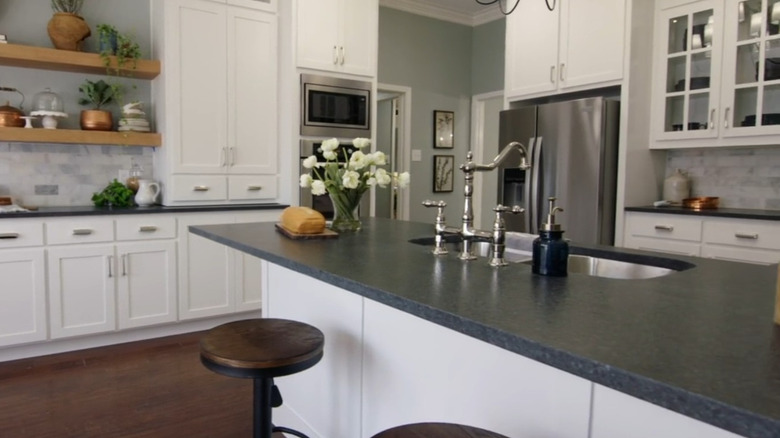 A kitchen with dark countertops and white cabinets