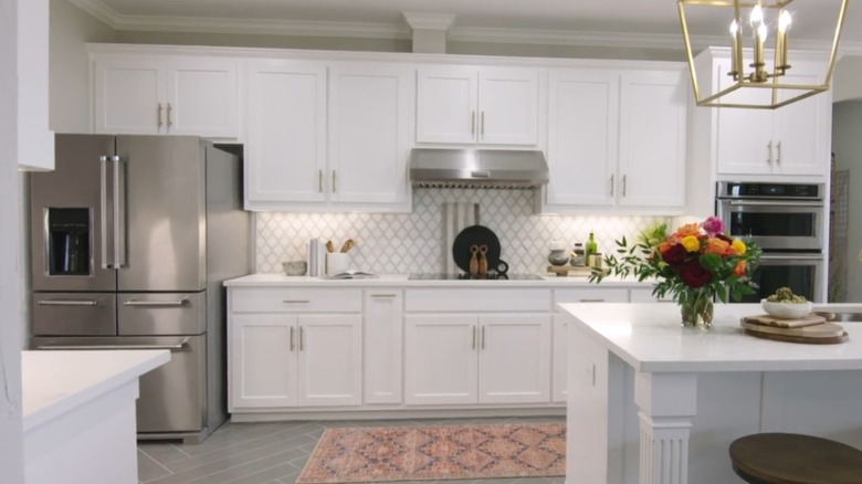 A kitchen with white cabinets and gold hardware