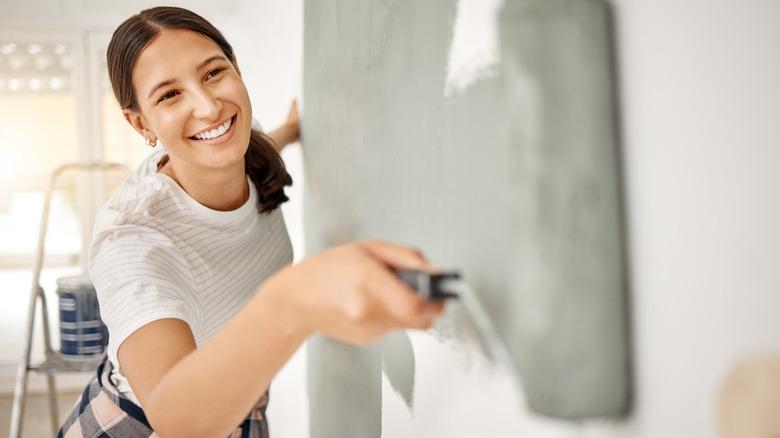 woman painting wall gray