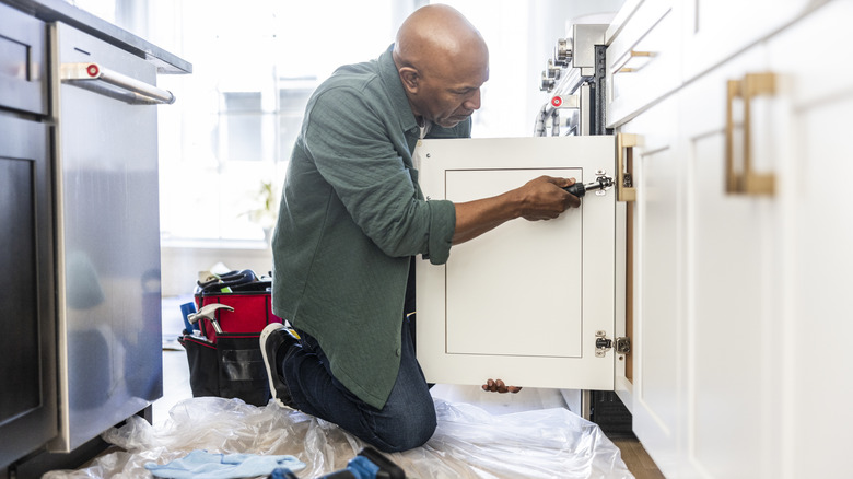 man installing kitchen cabinets