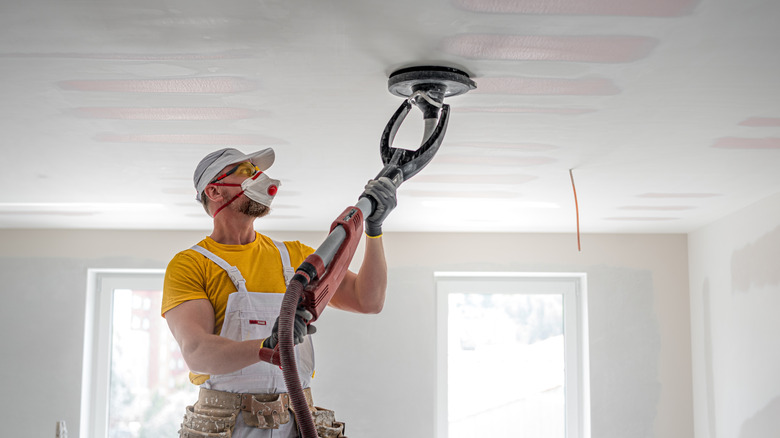 A person sanding down a ceiling