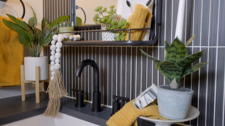 A bathroom sink with a black and white tiled wall behind it