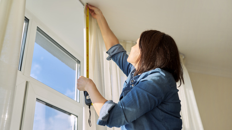 woman hanging curtains on window