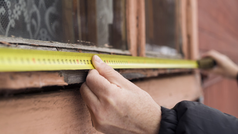 person measuring their window 