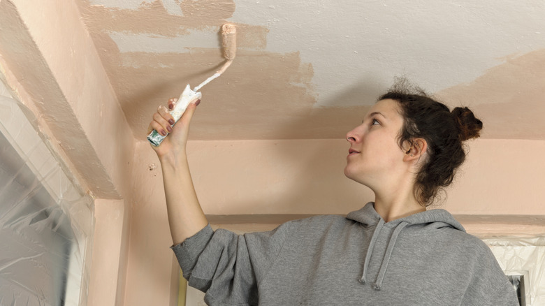 Woman painting ceiling beige