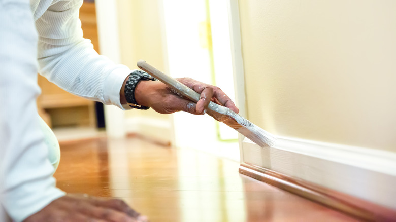 Person painting white baseboards