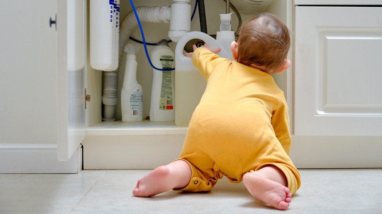 Baby touching chemicals in cabinet