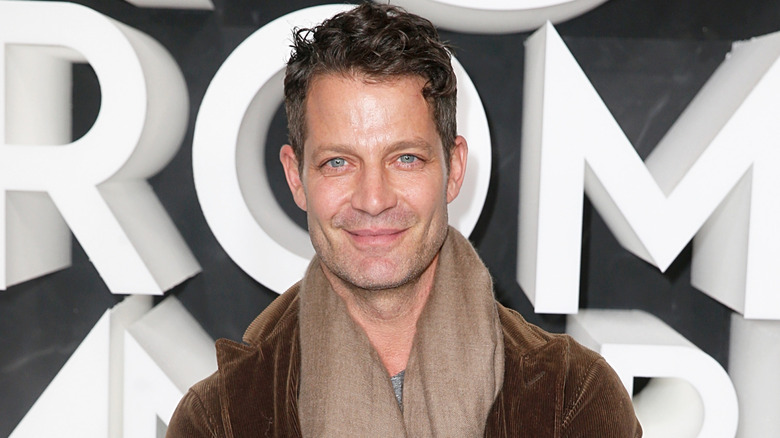 Nate Berkus in tan scarf grinning at event