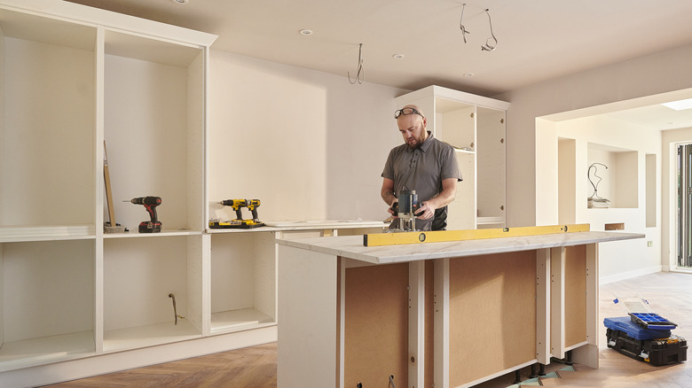 man installing kitchen cabinets