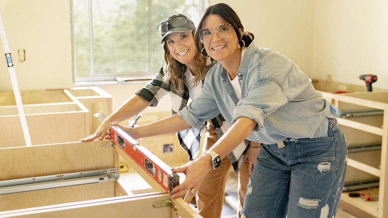 The hosts of HGTV's Unsellable Houses working on a renovation.