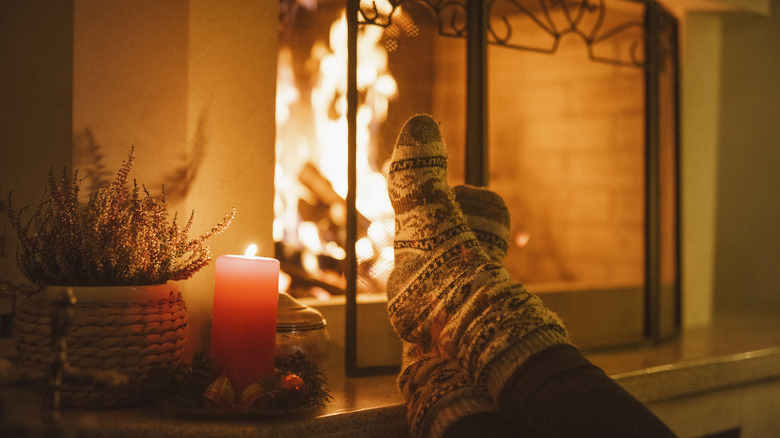 Person warming themselves up next to a traditional fireplace