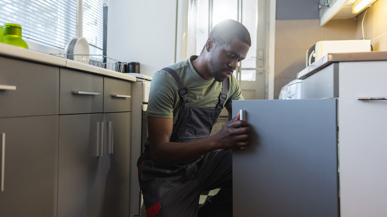 Man looking inside kitchen cabinet